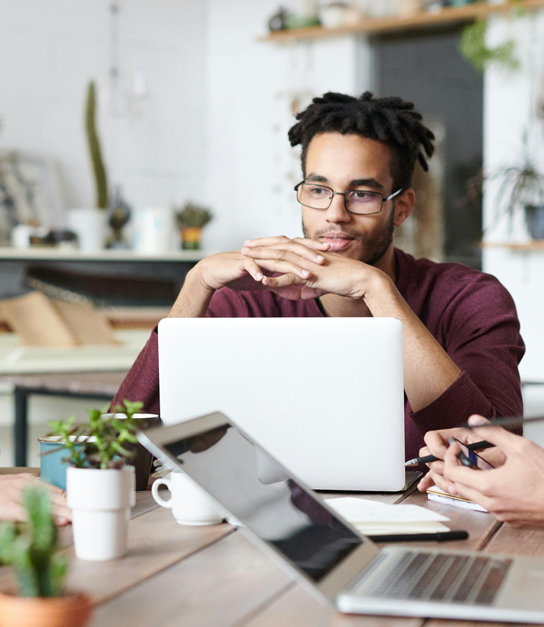Group discussion with laptops and coffee in a bright workspace.