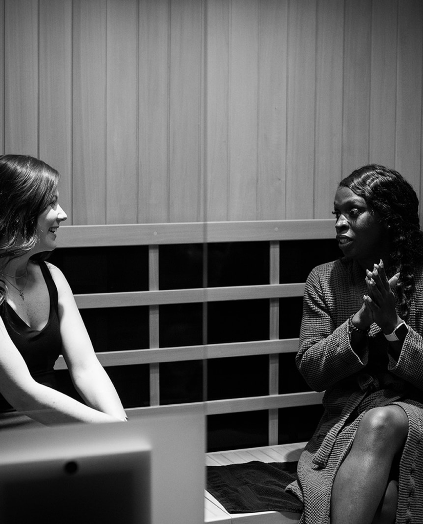 Two women enjoying a conversation in a sauna setting.